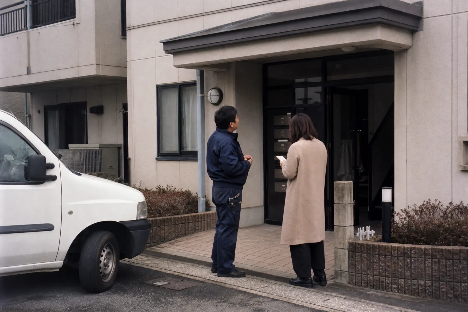 建物入口でお客様と打ち合わせをする作業スタッフ